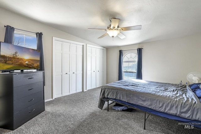 carpeted bedroom with vaulted ceiling, two closets, and a ceiling fan