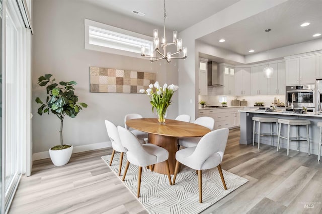 dining room featuring light wood-type flooring and an inviting chandelier