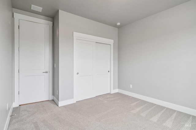 unfurnished bedroom featuring a closet and light carpet