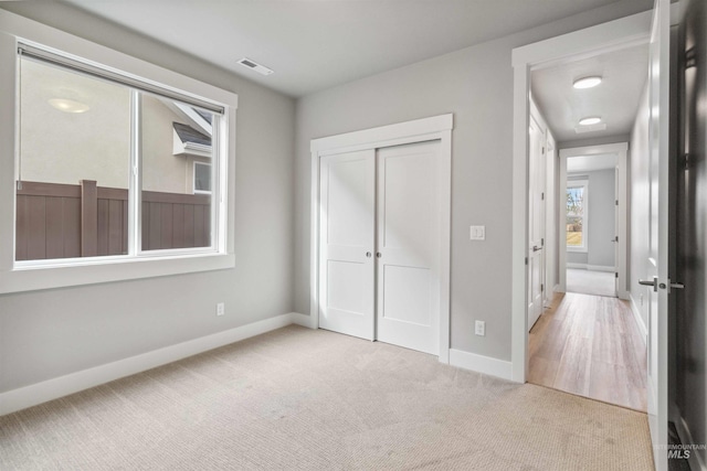 unfurnished bedroom with a closet and light carpet