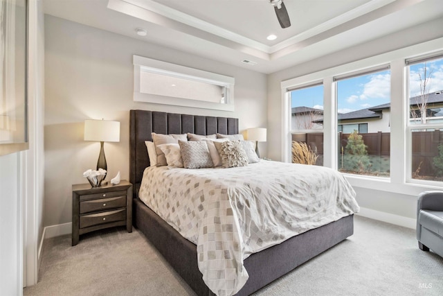 carpeted bedroom with ceiling fan and a tray ceiling