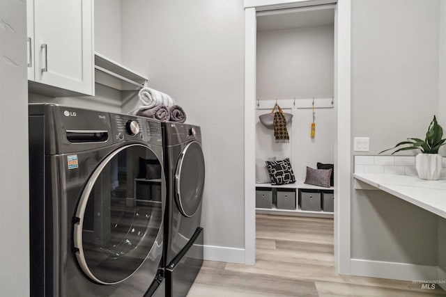 washroom with washing machine and dryer, cabinets, and light hardwood / wood-style floors