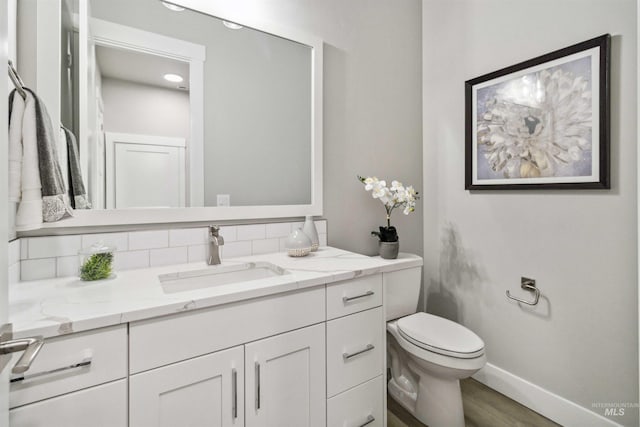 bathroom featuring tasteful backsplash, wood-type flooring, vanity, and toilet