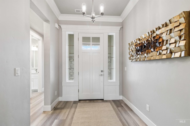 entryway with ornamental molding, light hardwood / wood-style flooring, an inviting chandelier, and plenty of natural light