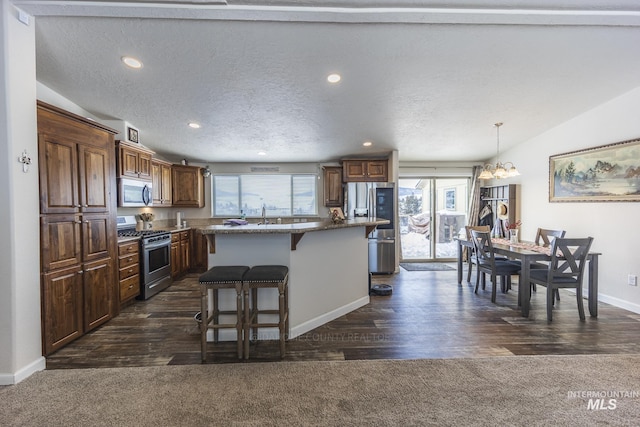 kitchen featuring stainless steel appliances, hanging light fixtures, vaulted ceiling, a kitchen island, and a kitchen breakfast bar