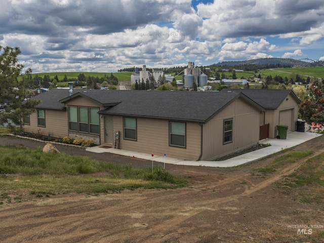 view of front of home with a garage, driveway, and a shingled roof