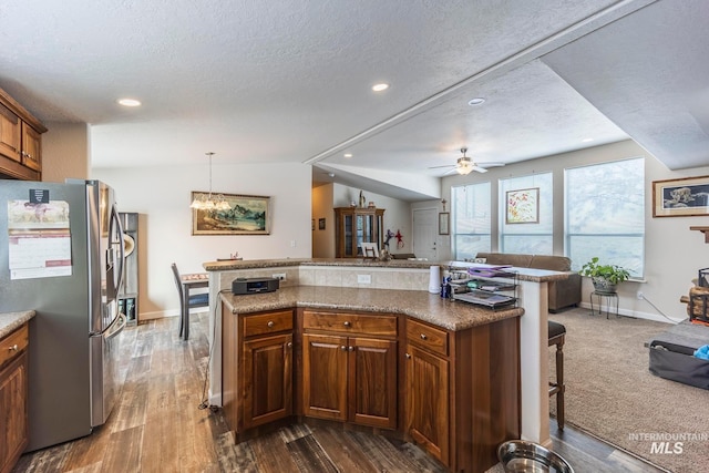 kitchen with a center island, a breakfast bar, open floor plan, and stainless steel fridge