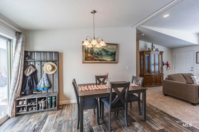 dining space with lofted ceiling, a notable chandelier, baseboards, and wood finished floors