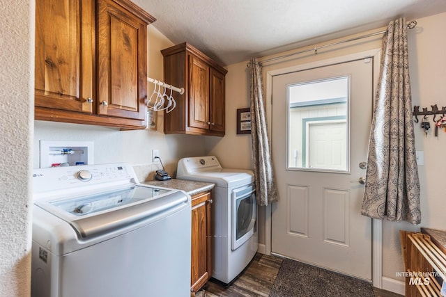 washroom featuring cabinet space, dark wood finished floors, and washing machine and clothes dryer