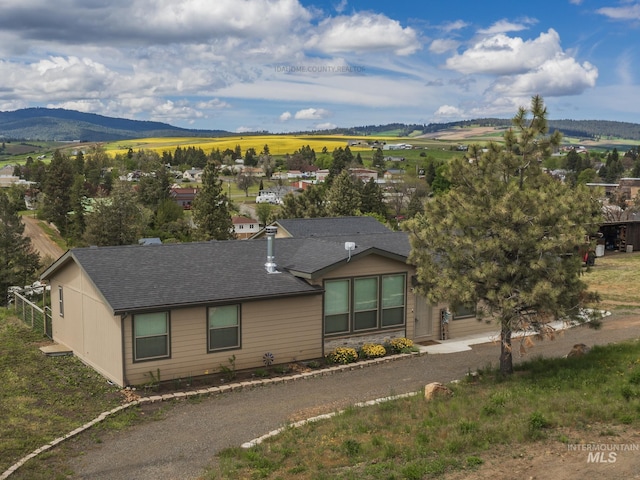 view of front of home featuring driveway, roof with shingles, and a mountain view