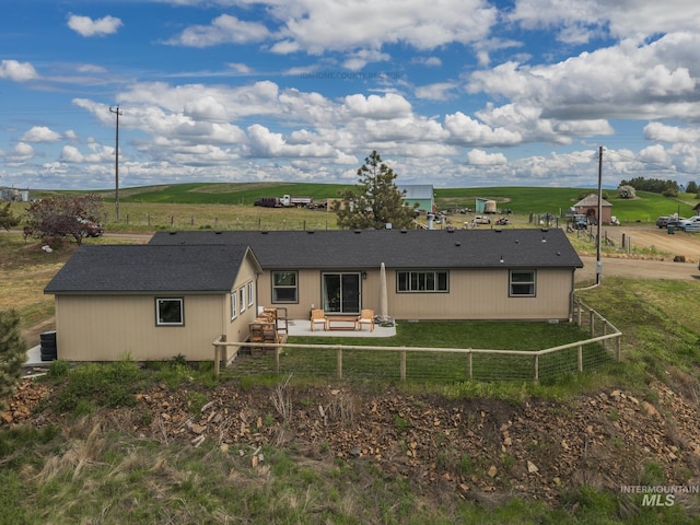 rear view of property with a rural view, a lawn, a patio area, and a fenced backyard