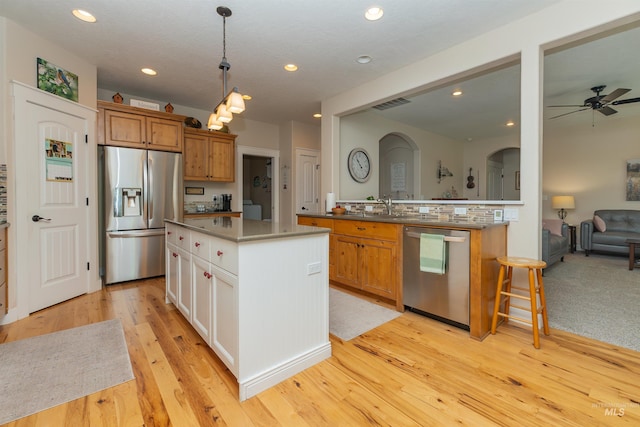 818 W Dallan Woods Way, Nampa, ID 83686 - kitchen with appliances with stainless steel finishes, arched walkways, ceiling fan, a kitchen island, and light wood-type flooring