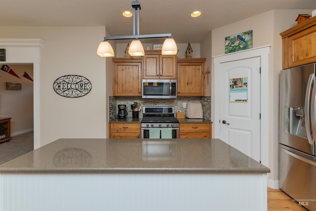 818 W Dallan Woods Way, Nampa, ID 83686 - kitchen featuring stainless steel appliances, backsplash, recessed lighting, hanging light fixtures, and brown cabinetry
