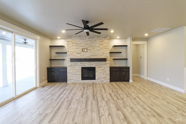 unfurnished living room featuring ceiling fan, a fireplace, and light wood-type flooring