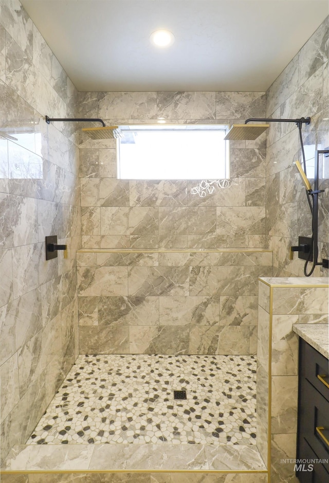 bathroom with vanity and a tile shower