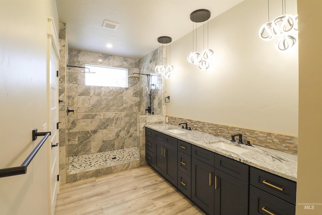 bathroom featuring vanity, tiled shower, hardwood / wood-style floors, and decorative backsplash