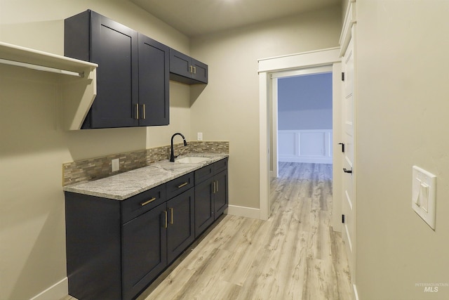 kitchen with light stone counters, sink, and light hardwood / wood-style flooring