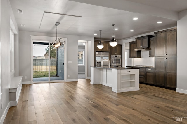 kitchen featuring a center island with sink, appliances with stainless steel finishes, dark brown cabinets, and pendant lighting