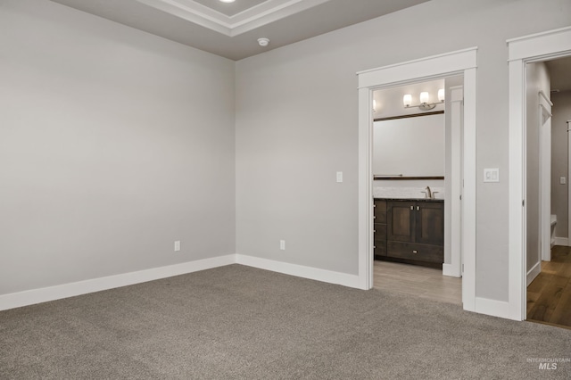 unfurnished bedroom featuring sink, ensuite bathroom, and carpet