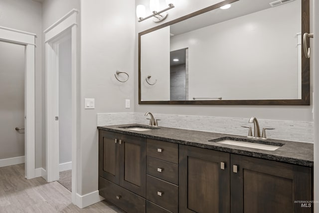 bathroom featuring vanity, wood-type flooring, and decorative backsplash