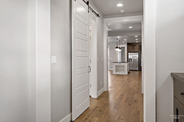 hall featuring hardwood / wood-style flooring, a barn door, and sink