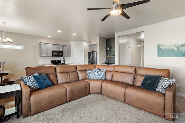 carpeted living room with ceiling fan with notable chandelier