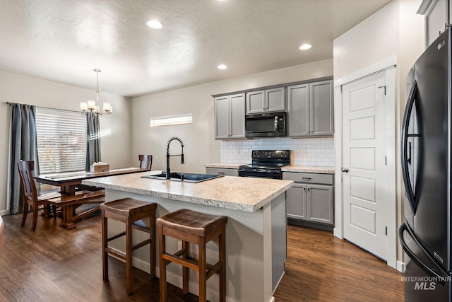 kitchen featuring gray cabinets, black appliances, a kitchen island with sink, and sink