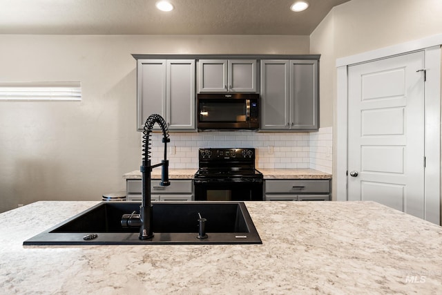 kitchen featuring gray cabinetry, light stone countertops, black range with electric cooktop, sink, and backsplash