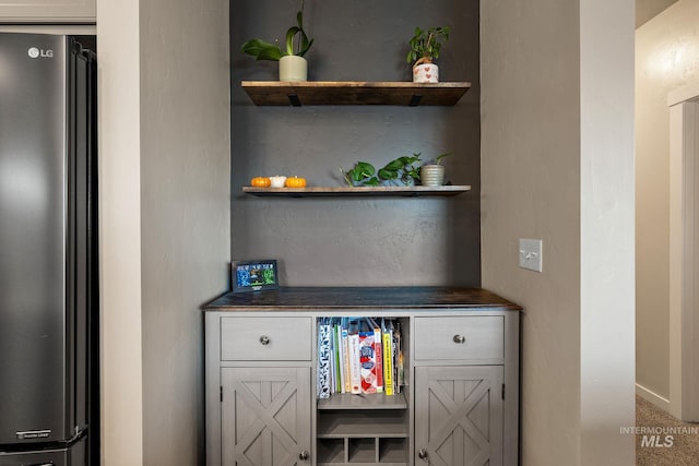 bar with refrigerator and carpet flooring