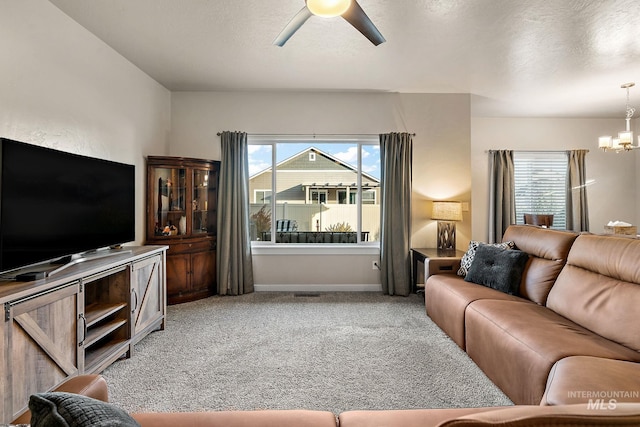 living room featuring ceiling fan with notable chandelier, light colored carpet, and a textured ceiling