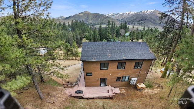 rear view of property featuring a deck with mountain view and roof with shingles