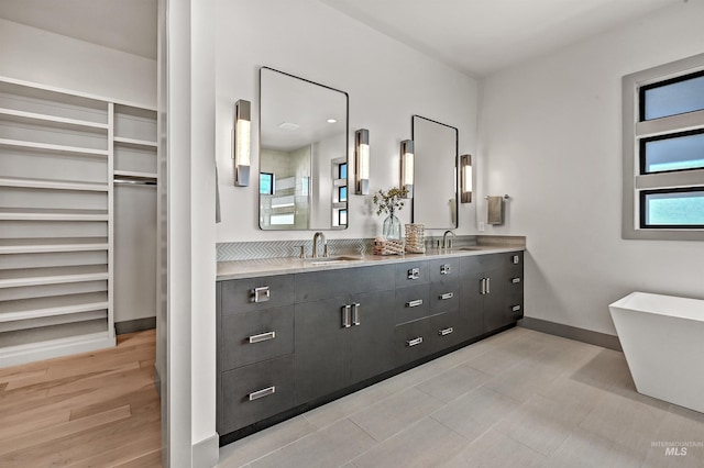 1771 S Riparian Way, Eagle, ID 83616 - bathroom featuring double vanity, baseboards, a freestanding tub, and a spacious closet