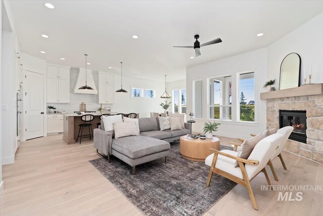 kitchen with wall chimney range hood, white cabinetry, sink, pendant lighting, and stainless steel appliances