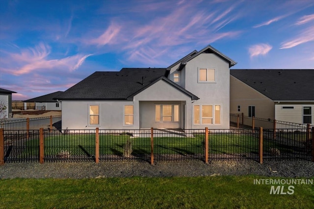 6511 W Donatella St, Eagle, ID 83616 - back of property at dusk with a lawn, stucco siding, and a fenced backyard