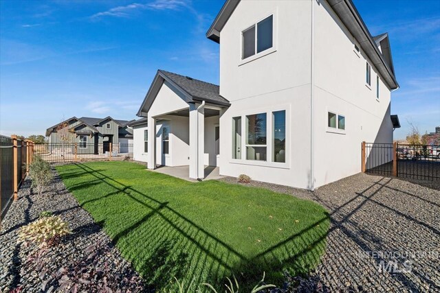 6511 W Donatella St, Eagle, ID 83616 - rear view of house featuring a lawn, a fenced backyard, stucco siding, and a patio