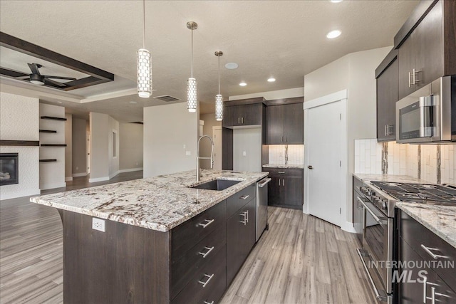 kitchen featuring a sink, light wood-type flooring, dark brown cabinetry, and appliances with stainless steel finishes