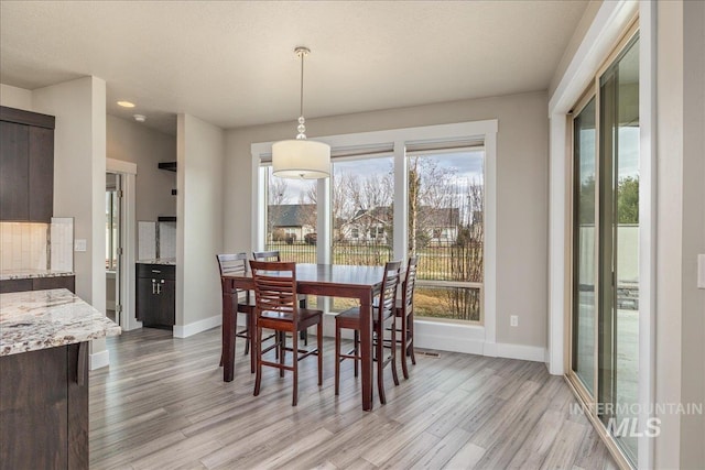 dining space with baseboards and light wood-style floors