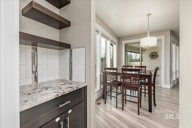 dining space with light wood-type flooring, baseboards, and visible vents