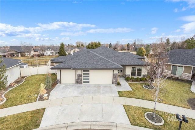 view of front of property featuring a front yard, concrete driveway, a garage, and stone siding