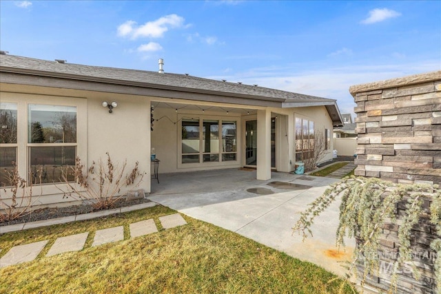 rear view of house featuring stucco siding, a patio, and roof with shingles