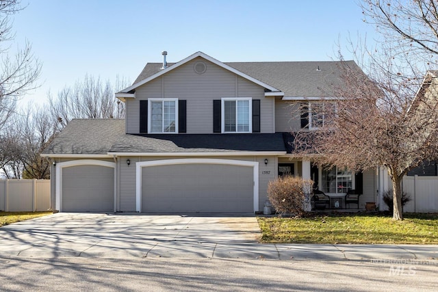 traditional home with an attached garage, a shingled roof, fence, concrete driveway, and a front yard