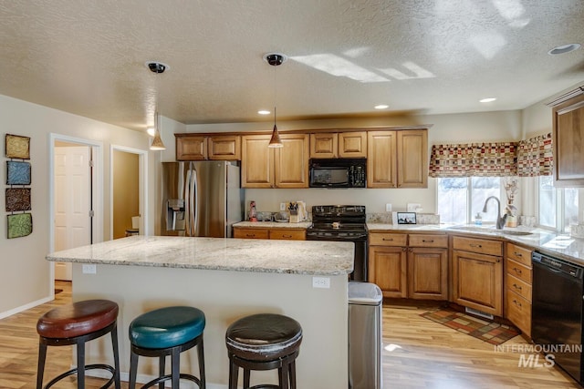 1587 N Firebrick Dr, Kuna, ID 83634 - kitchen featuring a breakfast bar area, a kitchen island, light wood-style flooring, and black appliances