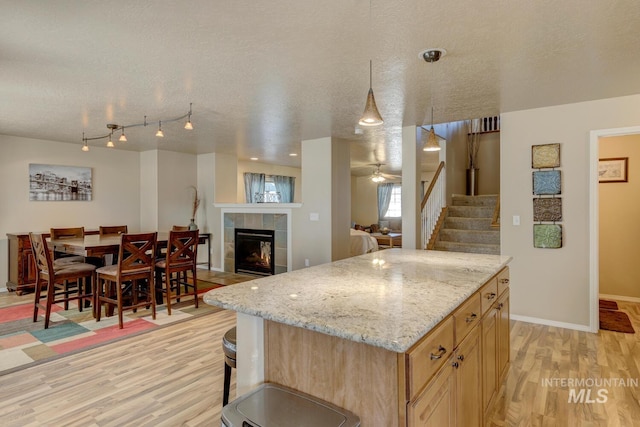 1587 N Firebrick Dr, Kuna, ID 83634 - kitchen with light stone countertops, light wood-style flooring, a textured ceiling, and a tile fireplace