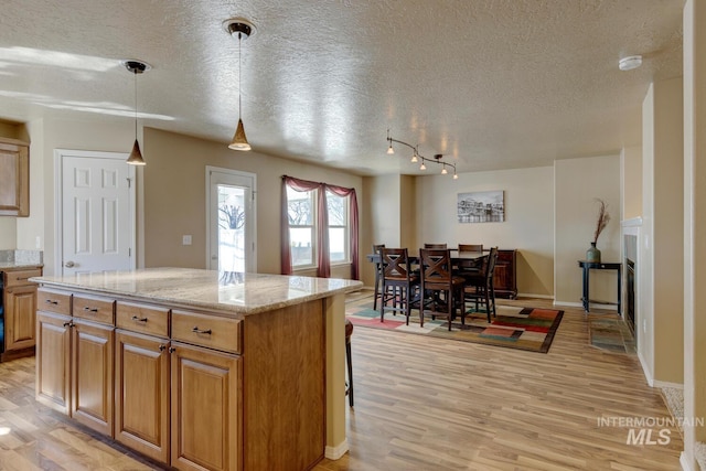1587 N Firebrick Dr, Kuna, ID 83634 - kitchen with a textured ceiling, light stone counters, a kitchen island, and light wood-style floors