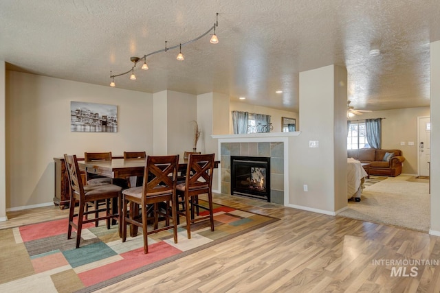 1587 N Firebrick Dr, Kuna, ID 83634 - dining room featuring a textured ceiling, a fireplace, wood finished floors, baseboards, and track lighting