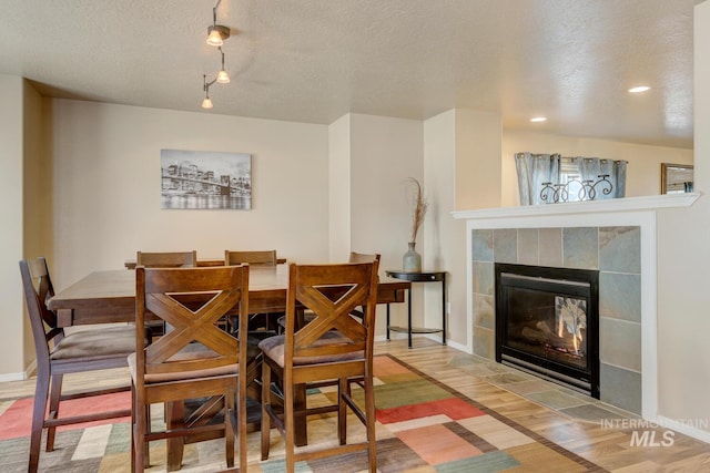 1587 N Firebrick Dr, Kuna, ID 83634 - dining space with a textured ceiling, a tiled fireplace, wood finished floors, and baseboards