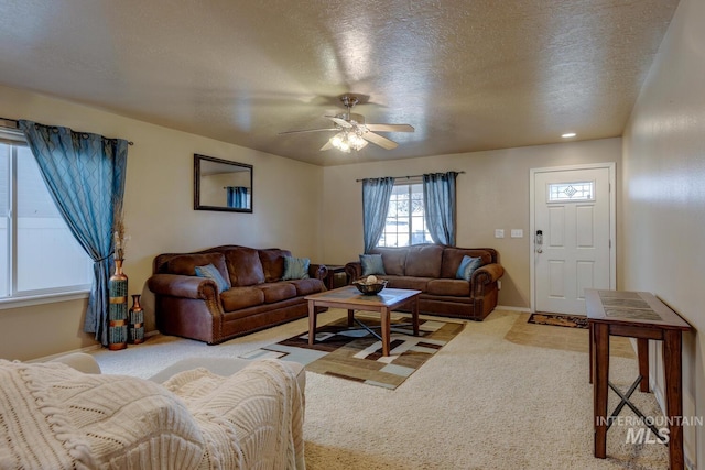 carpeted living room with ceiling fan, baseboards, and a textured ceiling