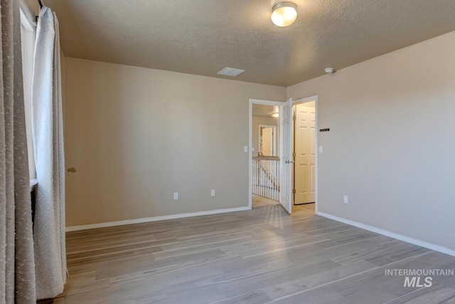 1587 N Firebrick Dr, Kuna, ID 83634 - unfurnished bedroom with light wood-style floors, visible vents, a textured ceiling, and baseboards