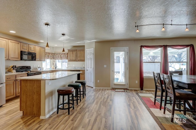 1587 N Firebrick Dr, Kuna, ID 83634 - kitchen featuring a breakfast bar area, light wood-style floors, light countertops, a center island, and black appliances