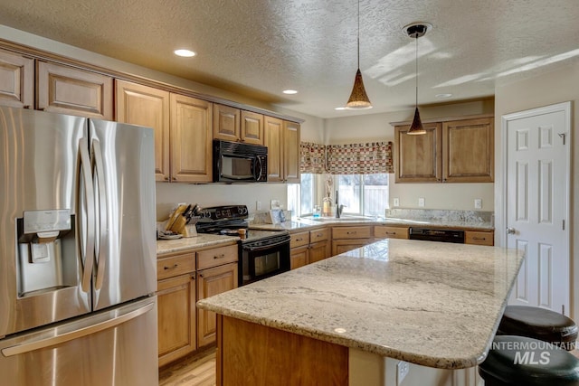 1587 N Firebrick Dr, Kuna, ID 83634 - kitchen featuring light stone countertops, black appliances, a kitchen island, and a breakfast bar area